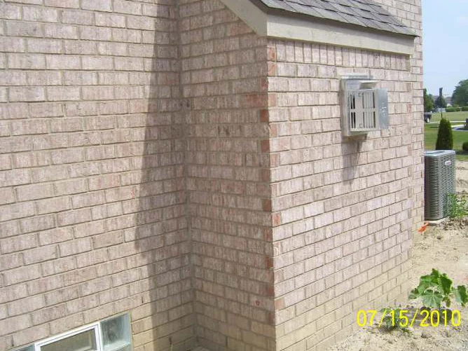 The rear corner of the house by the dryer vent in July 2010, orange headers stepping up the return where the shadow falls across it