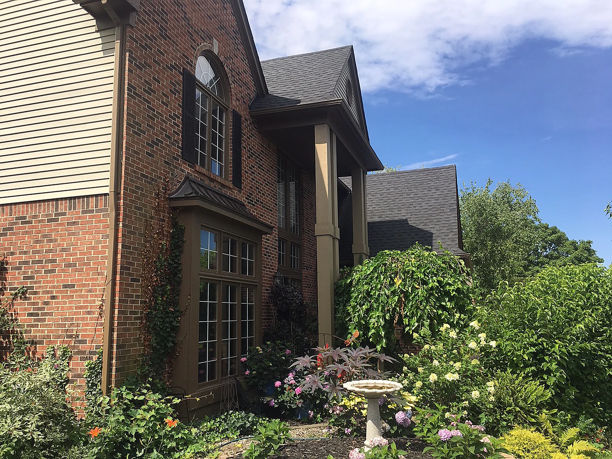 The bay window and the wall above it seen from below in 2019, the brick an even red and brown blend running up to the eaves
