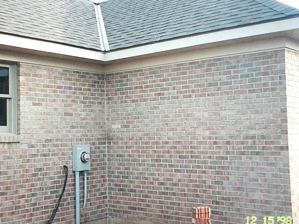 An outside corner of the house in 1998, the brick a patchy mix of pink, grey and pale tan units that do not sit in one range