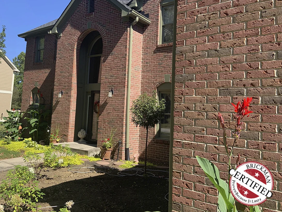 The entry gable seen along the front wall in 2019, the near brick and the far brick holding the same red and brown range