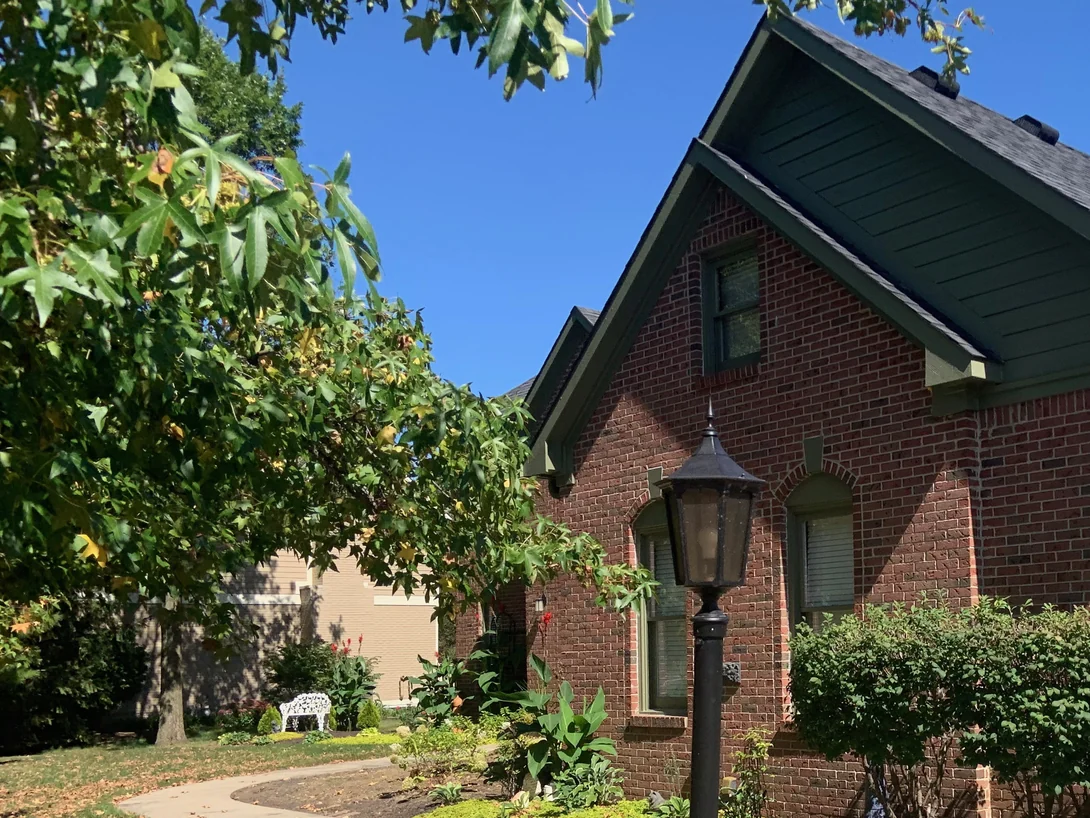 The gable end of the house in 2019 beside a lamp post, its brick evenly colored from the beds up to the eaves