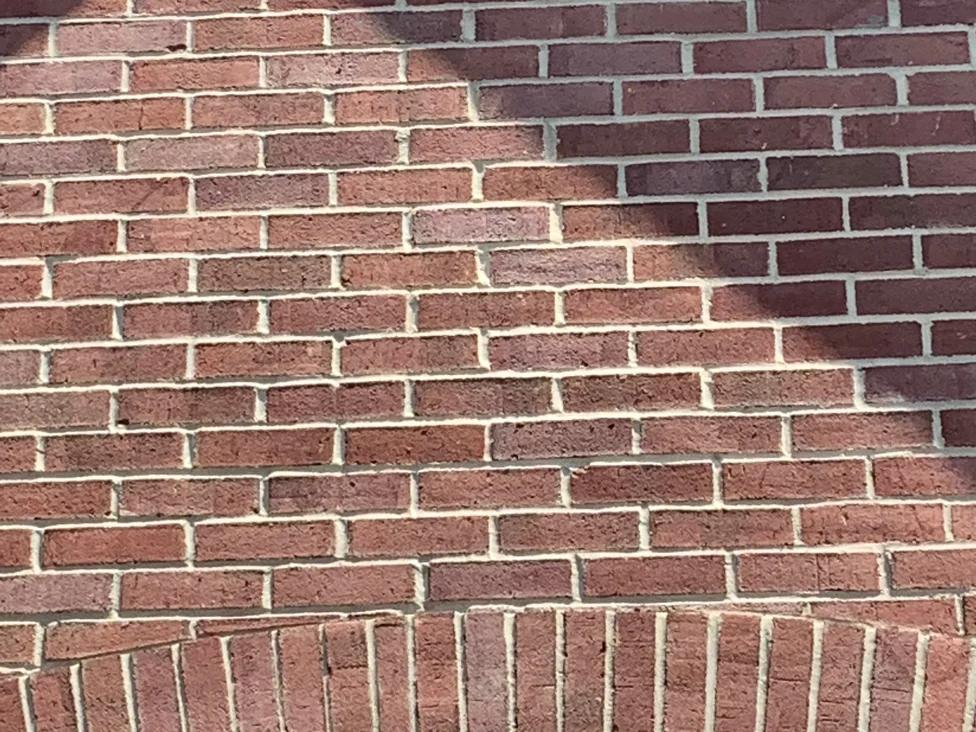 Close view of the gable brick in 2019, a blend of red, rose and deep purple units running down to the arch of upright bricks over the window