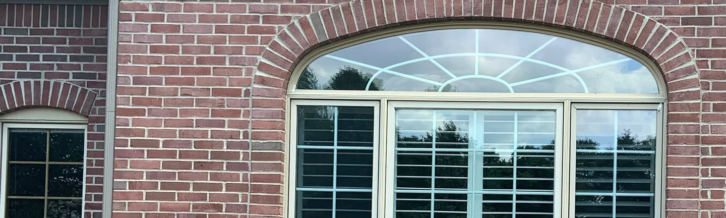 The gable end of a Carmel, Indiana home in 2019, its brick an even red range around the arched window
