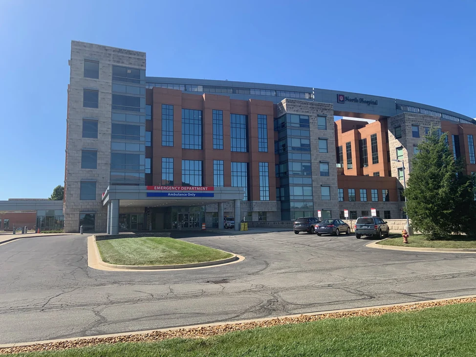 The medical center from its approach road in 2019, brick bays and a limestone stair tower rising above the emergency department canopy.