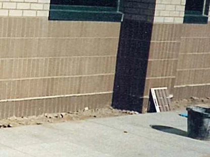 The test area in 1995, a darkened strip of base brick running down from a window sill, with a sample panel leaning against the wall at the right