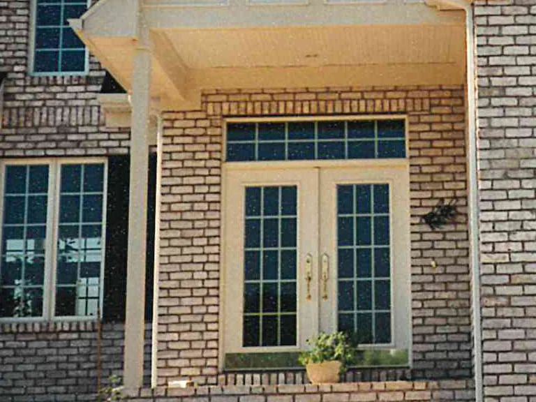 The front entry in 1997 after staining, the brick either side of the white double doors reading as one range under the porch roof