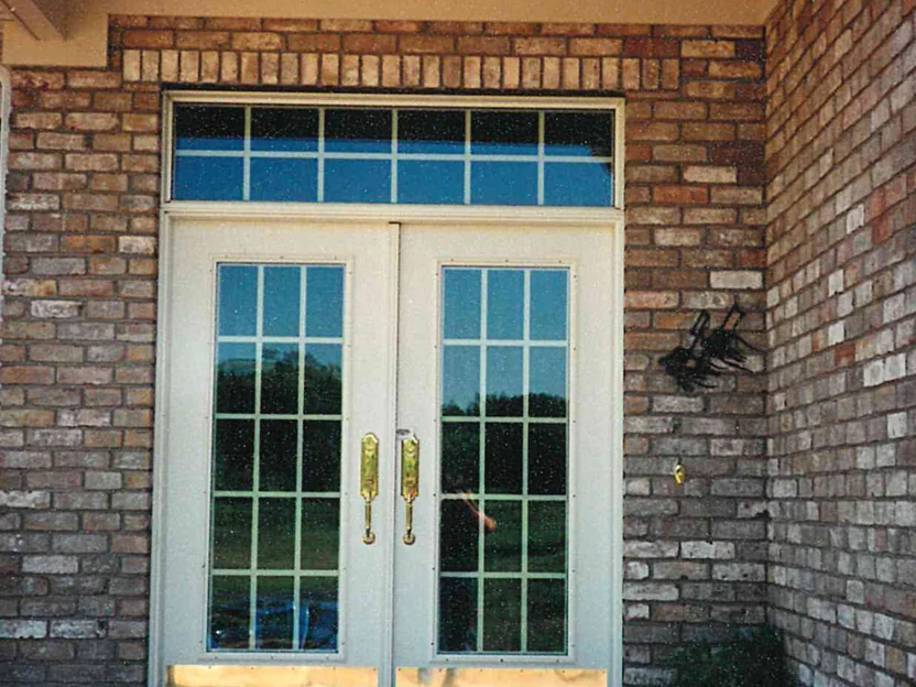 The front entry in 1997, white double doors with a transom under a soldier course, dark units patched through the brick on both sides