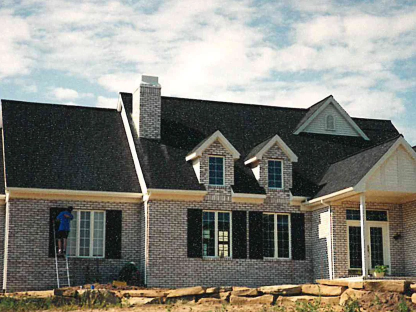 The front of the house during the 1997 work, an applicator on an extension ladder at the far left window and the wall around him already lightened