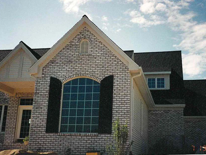 The same gable end in July 1997 after staining, the brick around the arched window reading as one buff range, the camera date in the corner