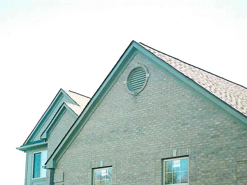 The same gable end from the front in 2002 once the work was done, the wall holding one pale buff range from the ridge down past the round vent to the window heads