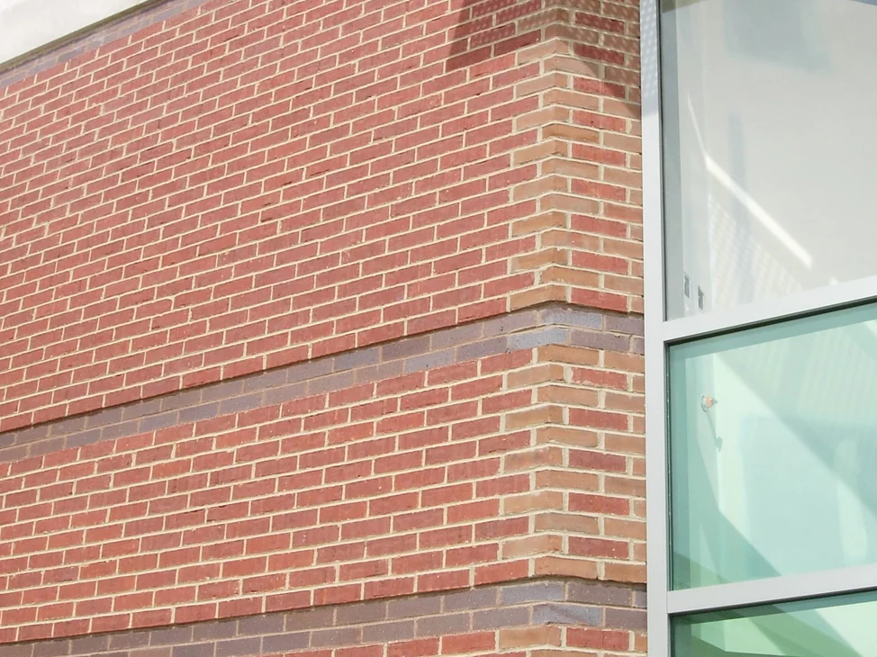 The 135 degree corner of the bank in 2004 before staining, red brick with two dark accent courses and the corner units reading lighter than the wall, a window bay to the right