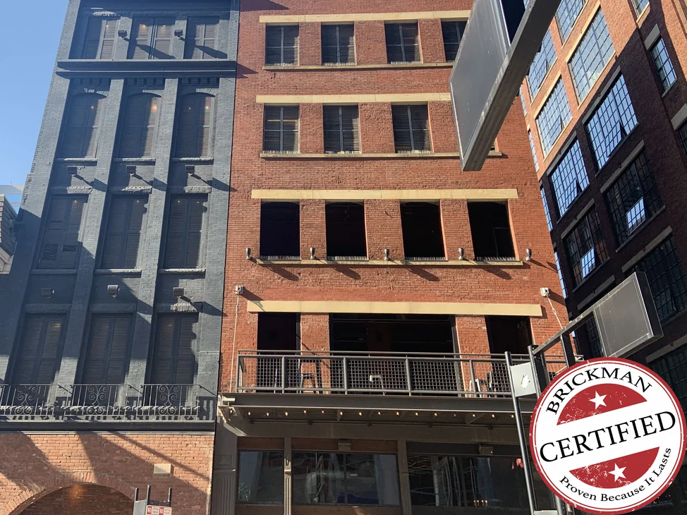 The building from the street in 2019, four floors of stained brick above the entrance with pale stone lintels at each level.