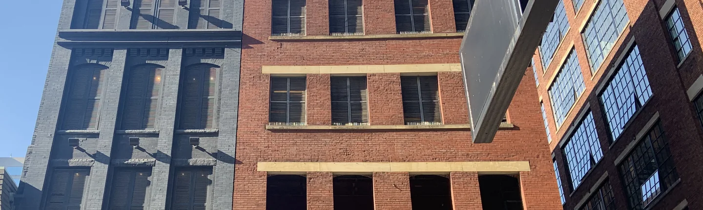The upper brick elevation in 2019, pale stone lintels running across four floors of windows
