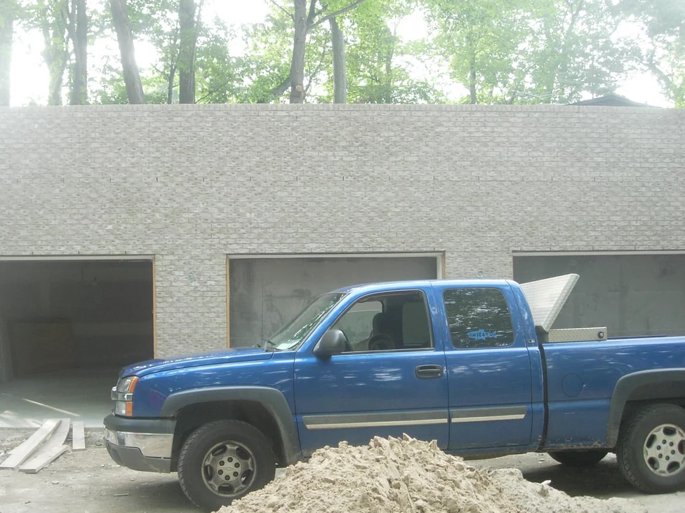 The new garage wing still under construction in 2008, its brick a flat pale grey and cream, with the three door openings unfitted and a pickup parked on bare ground