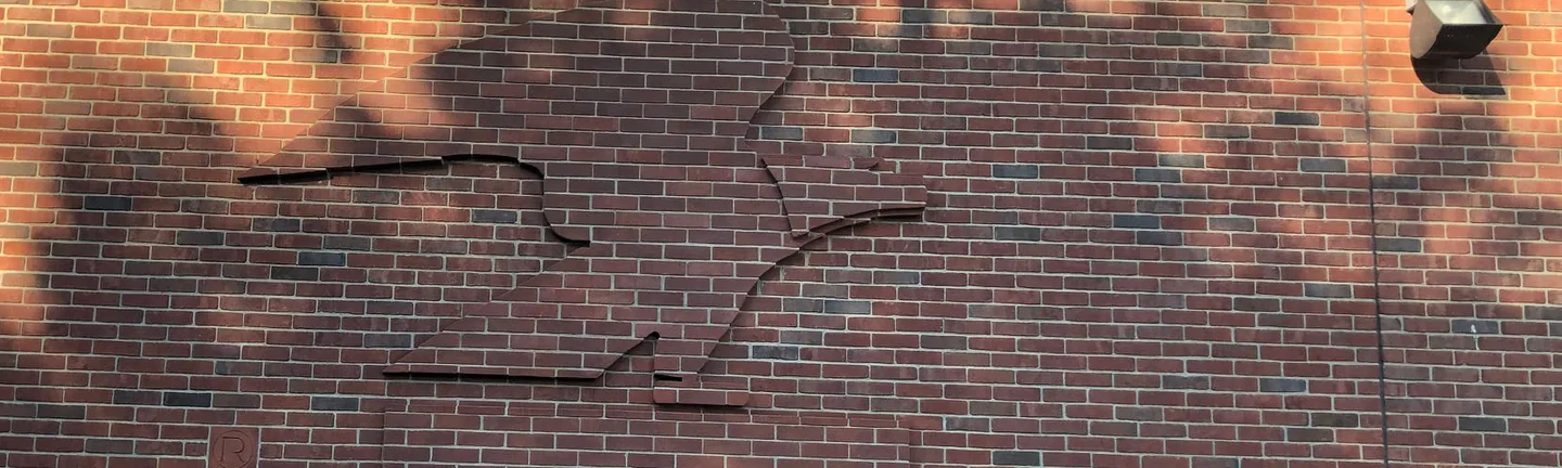 The eagle wall of the Covington post office in 2019, sculpture and field brick reading as one dark red range