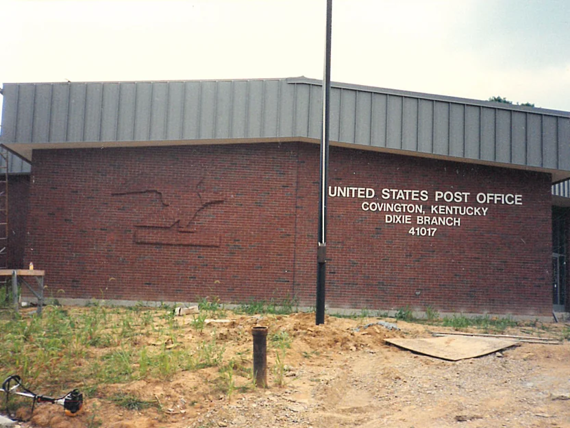 The single storey post office from the graded forecourt in 1994, its name in cast letters on the front wall and the brick eagle on the return