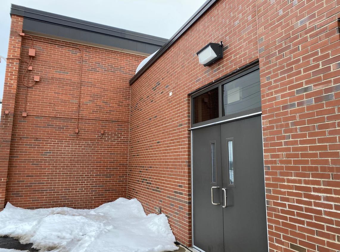 The corner of a school in Crest Hill in 2021, snow against the wall and the brick one even red fourteen years after staining