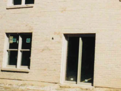 The window wall of the house during the work in 1998, buff brick around a double window and a sliding door still carrying their factory labels