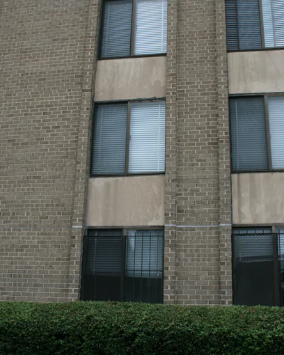 Window bays and brick piers on a Washington, DC apartment block in 2019, eight years after staining