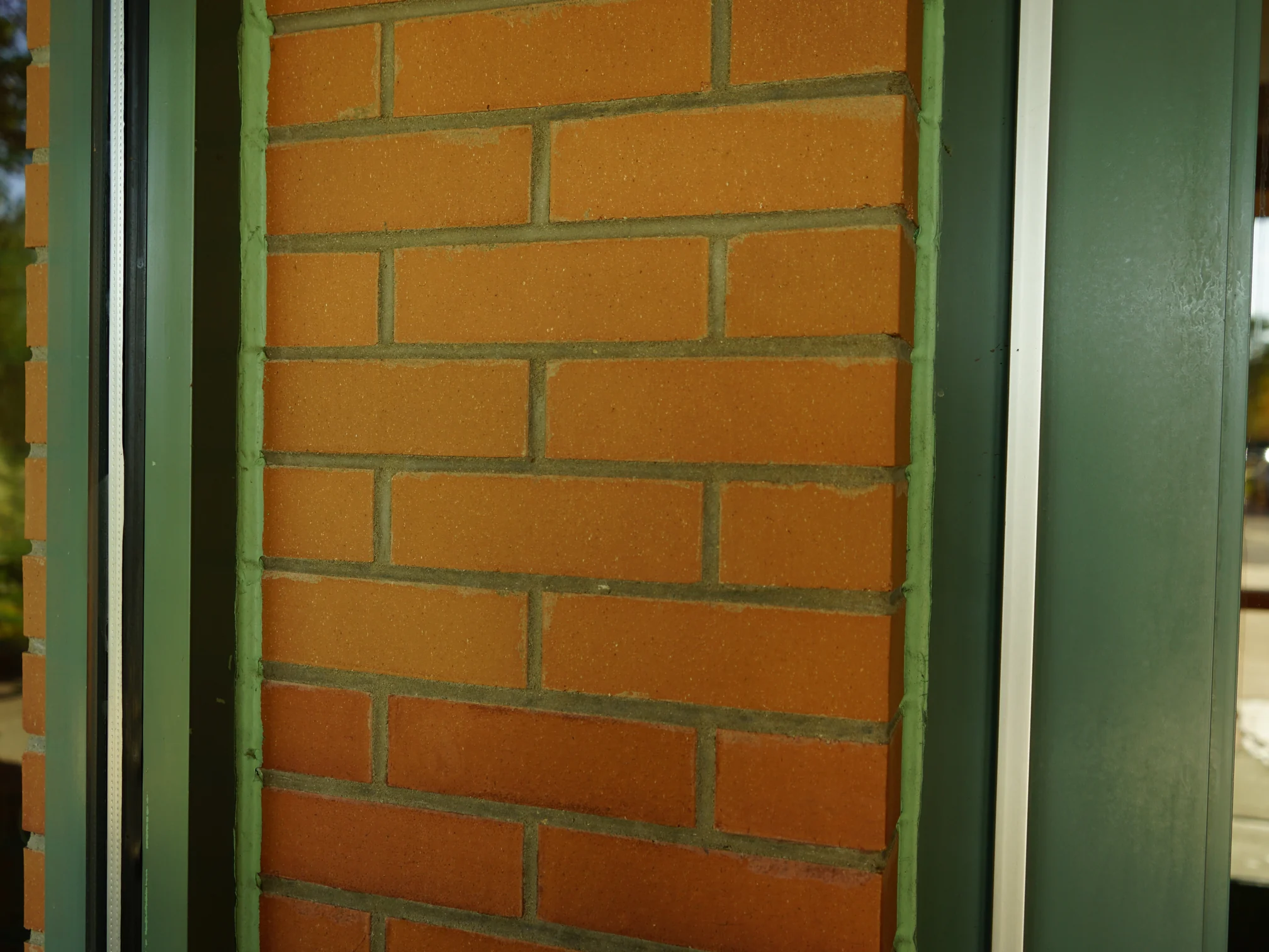 A brick pier beside the entrance doors in 2019, the courses shifting from lighter tan at the top to a deeper orange band lower down