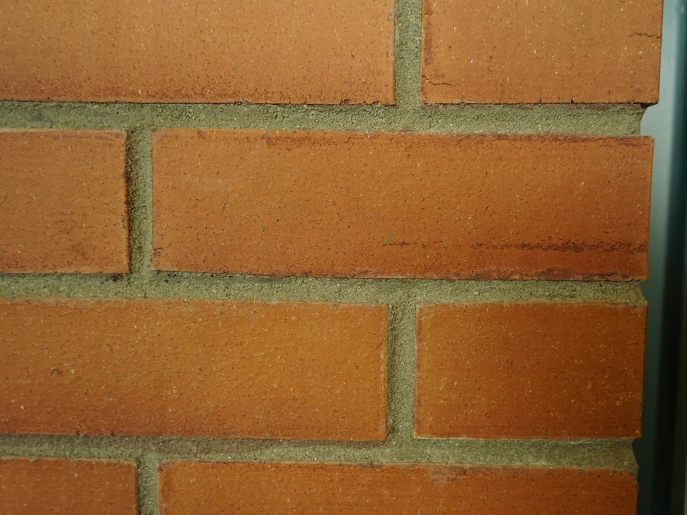 Close view of the brick at unit scale in 2019, the faces running orange through red with pale mortar joints between them