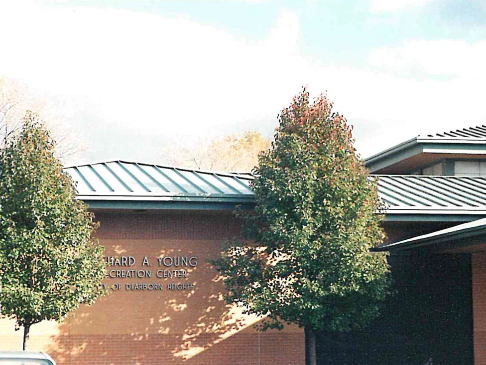 The long name wall of the recreation center in 2000, one flat red brown across the whole elevation, with the building's cast lettering and two young trees in front