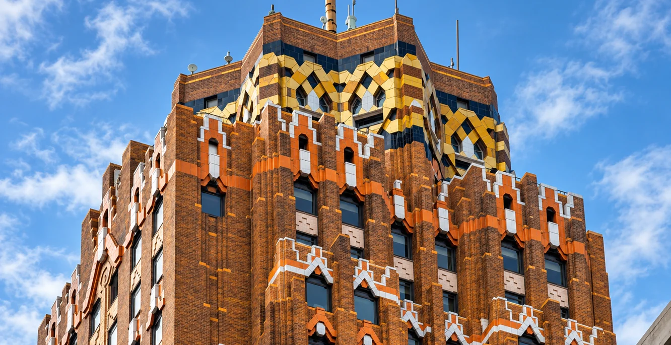 The Art Deco crown of the Guardian Building in downtown Detroit, orange brick and patterned tile against a blue sky