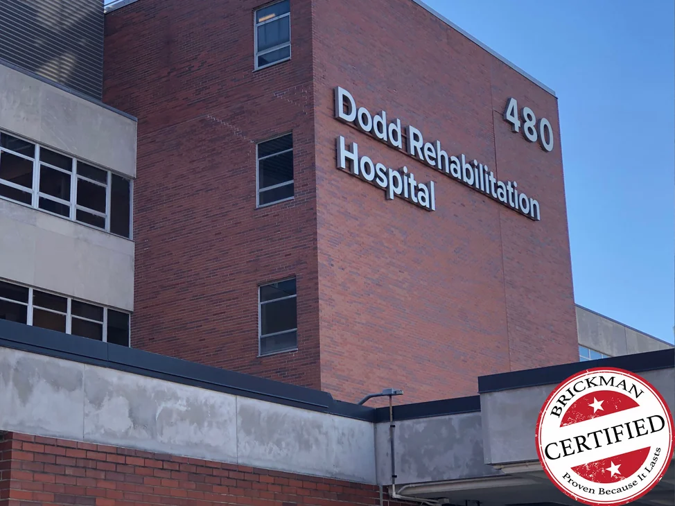 The brick block above the hospital entrance in 2021, one red range from the canopy to the parapet under the Dodd Rehabilitation Hospital letters, with the certification stamp in the corner