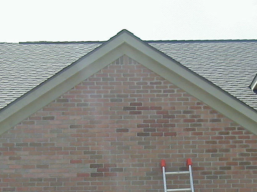 The same gable partway through the work in 2004, an extension ladder standing against the wall and darker units worked into the range above it