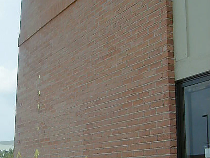 The outside corner of the office in 2005, the wall carrying broad areas of darker brick with small yellow marks set against them