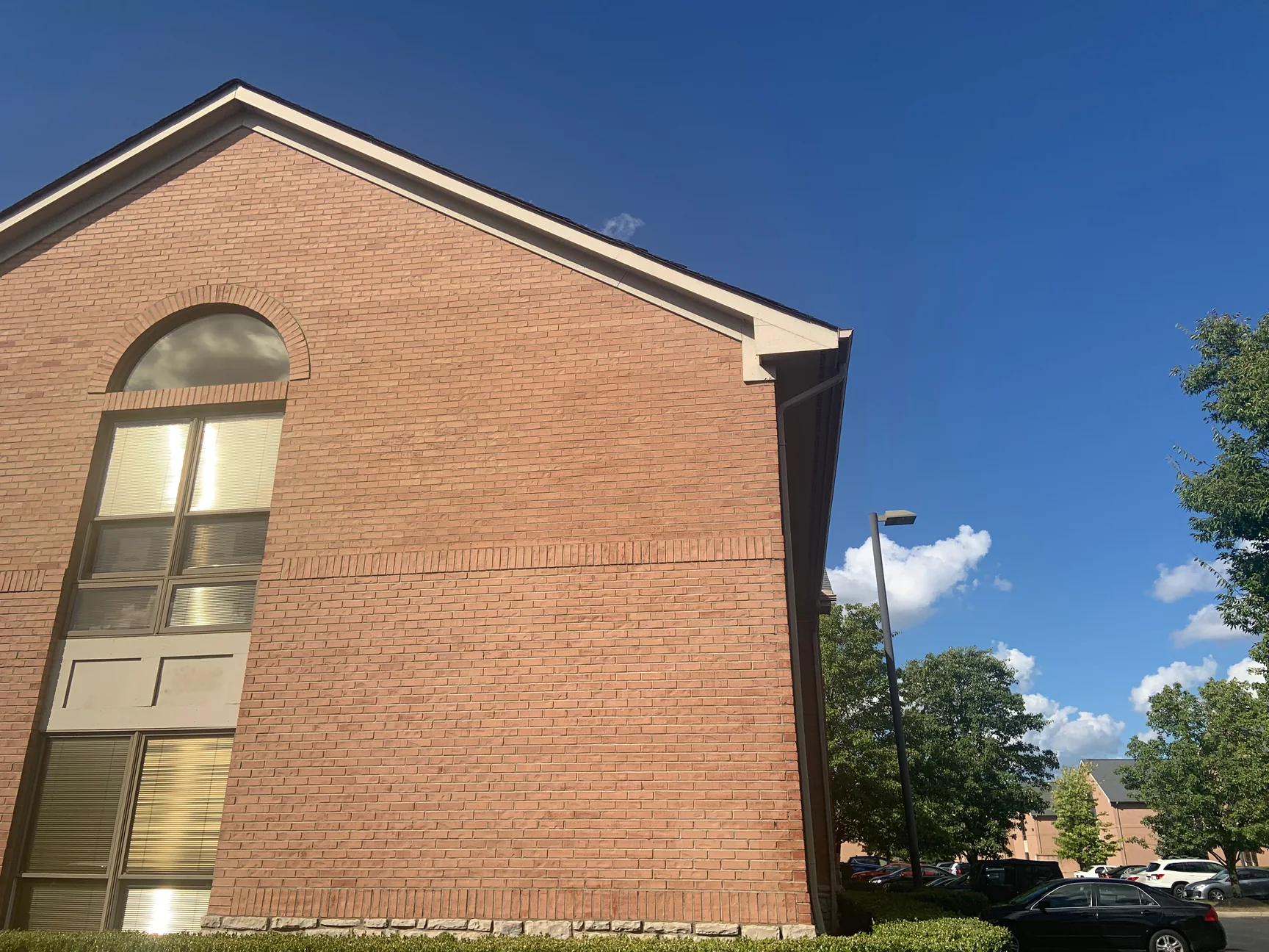 The gable end of the office in 2019, the brick carrying one even red range from the stone base up to the roof line