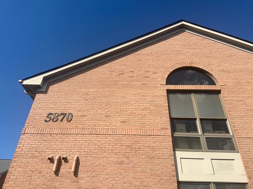 The gable of the office seen from below in 2019, the brick arch over the tall window and the wall around it in one even red range