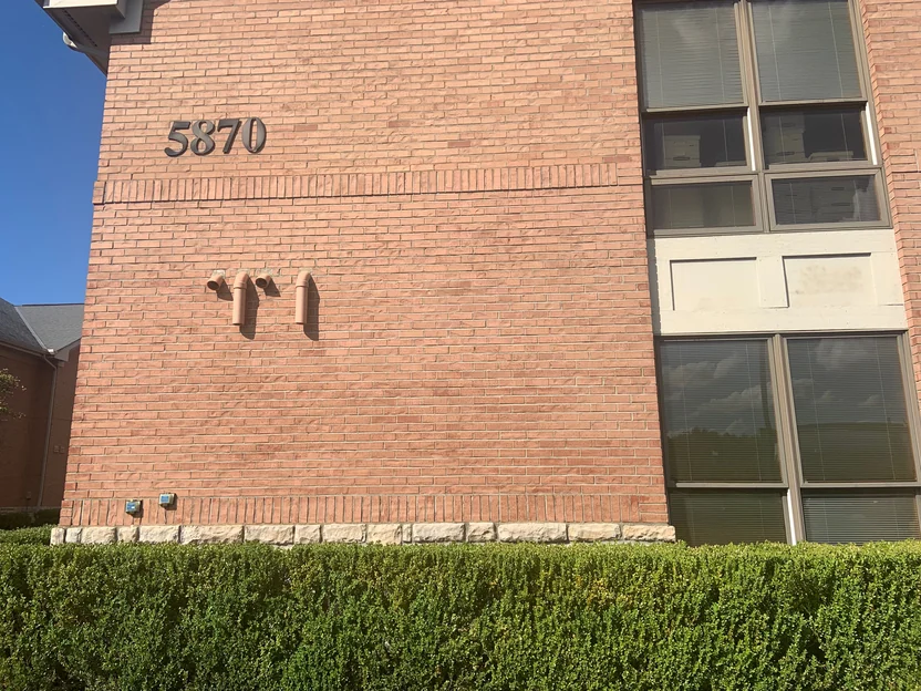 A wall of the office at close range in 2019, the brick reading as one red range above and below the banded soldier course