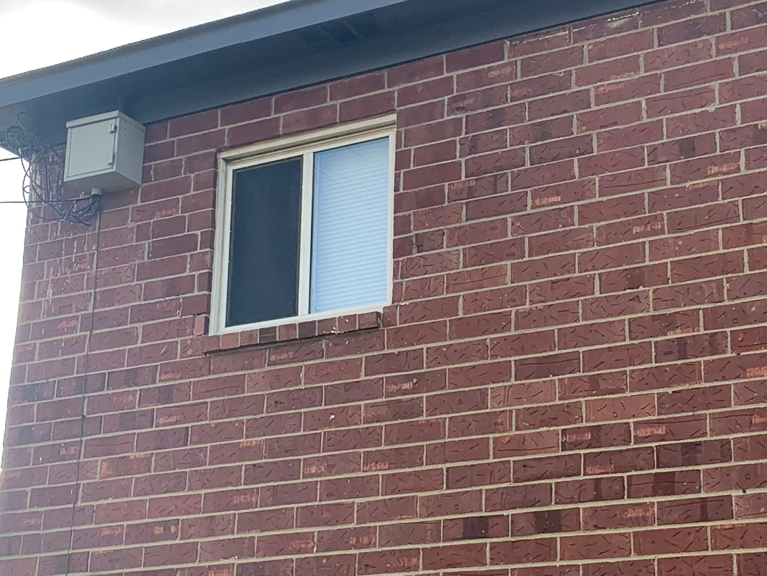 The upper wall around the same window in 2019, an electrical box under the eaves and the brick reading as one red range across the repaired area and the original beside it