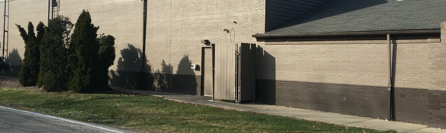 The long side wall of the Elyria restaurant in 2020, its brick under one grey tan finish with a darker band at the base