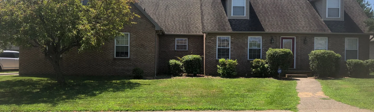 The front of the house from the street in 2019, its brick reading as one tan and brown range across the garage wing, the dormers and the entry