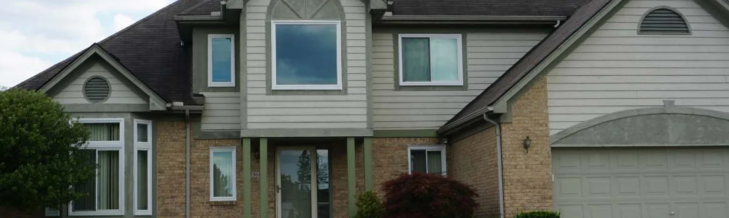 The brick ground floor of the Farmington Hills house in 2019, tan brick one even range from the bay window past the entrance to the garage