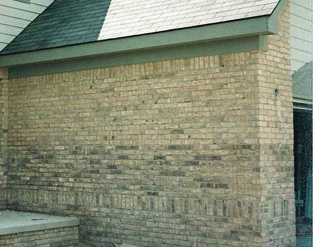The gable end wall in 1998 before the work, dark units concentrated in the bottom third of the wall and in the soldier course above the foundation