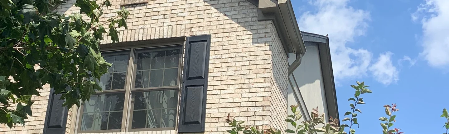 Brick and a shuttered upper window on a Fishers house in 2019, the wall one even cream and buff range