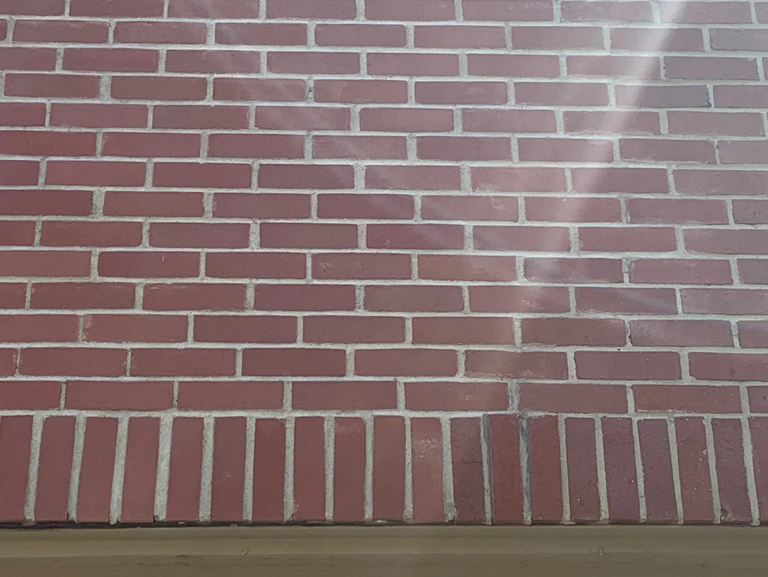 The same wall above the garage in 2019, the brick a deeper red and the joints a warm buff, the soldier course over the opening reading with the courses above it