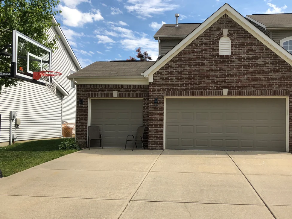The house from the driveway in 2019, the two-car garage gable and the single bay beside it reading as one brick range