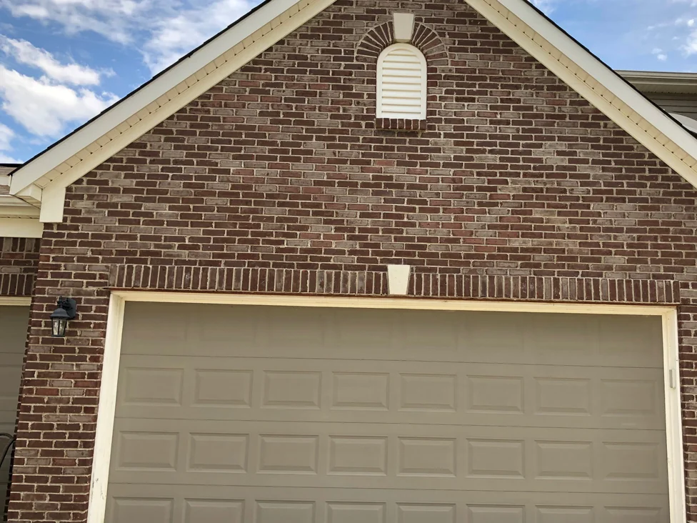 The garage gable in 2019, brick running from the soldier course over the opening up to the ridge with a louvred vent set in an arch