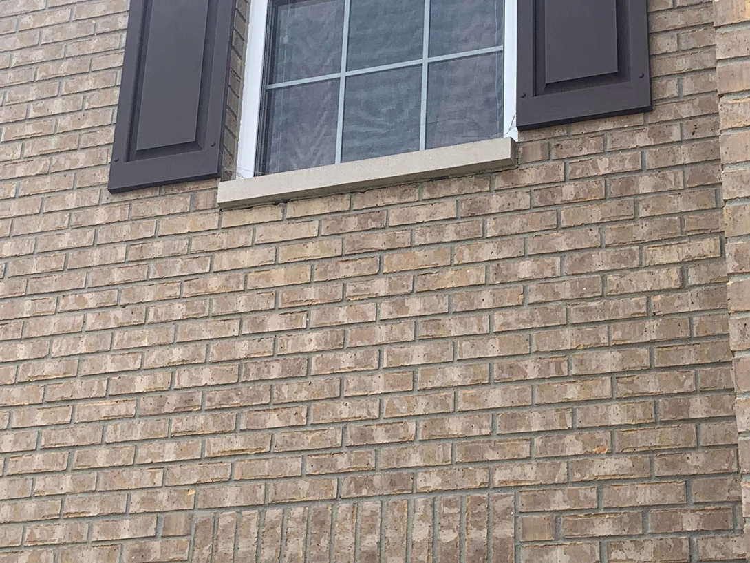 Close view under a cast stone window sill in 2019, the brick below the sill carrying the same buff and tan range as the units either side of the opening