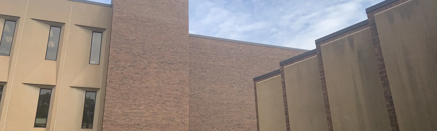 The brick stair tower and adjoining wing of Neff Hall in 2019, the brick reading as one red and brown range
