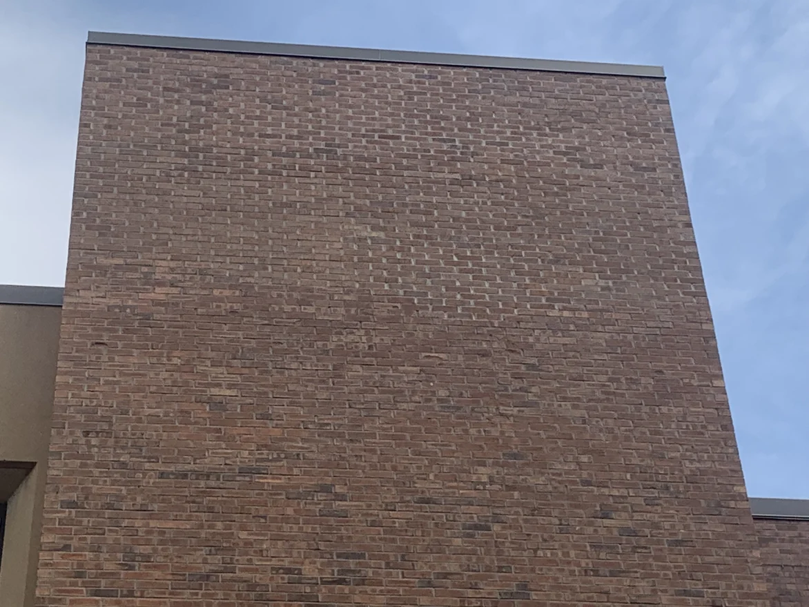 Another windowless brick face of the building in 2019, its courses running unbroken to the coping