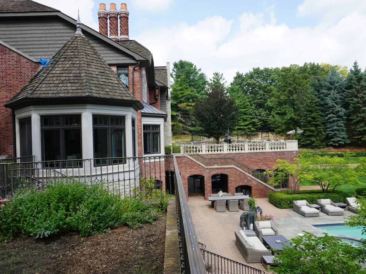 The bay window wing and its chimney stacks seen from above the terrace in 2019, with the pool and garden below