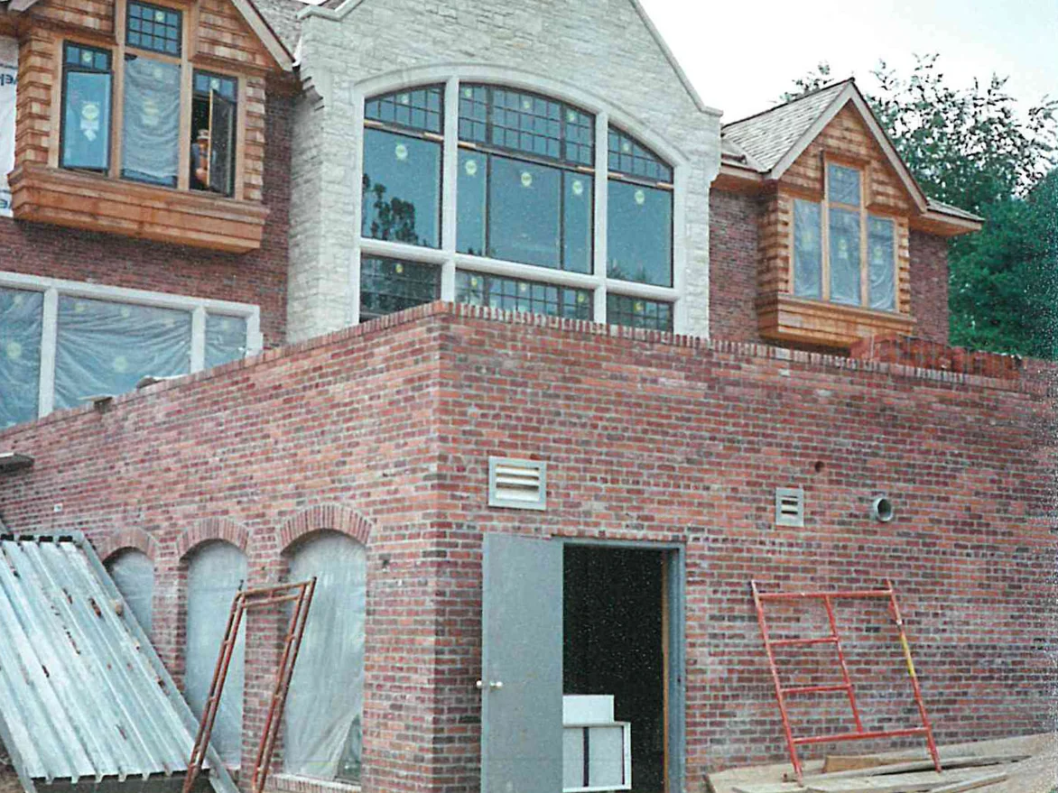 An outside corner of the terrace wall in 1997, scaffold frames leaning against it and the gabled wing above still wrapped in housewrap