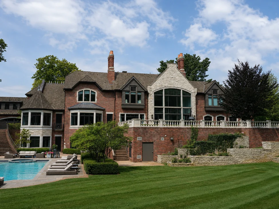 The rear of the house across the lawn in 2019, its brick reading as one even range from the terrace wall up to the gables