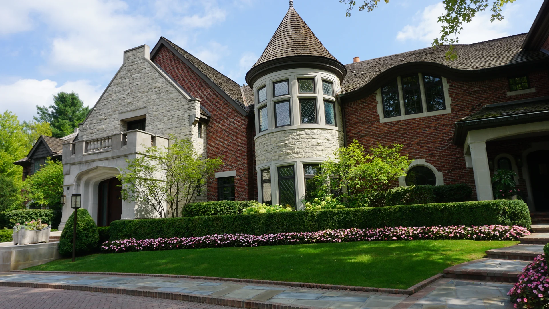 A brick and stone house with a round turret in Franklin, Michigan in 2019, its red brick one even range