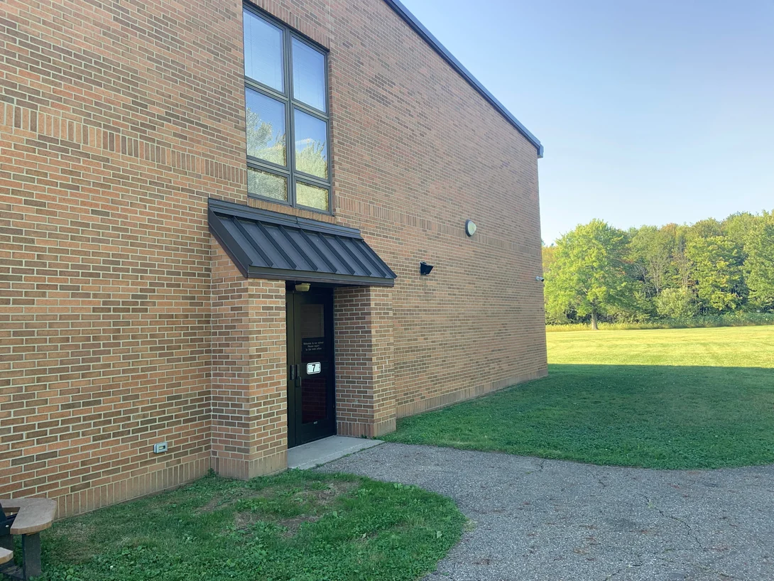 A side elevation of the school in 2019 running to the corner, the brick even from the ground to the parapet past a canopied doorway